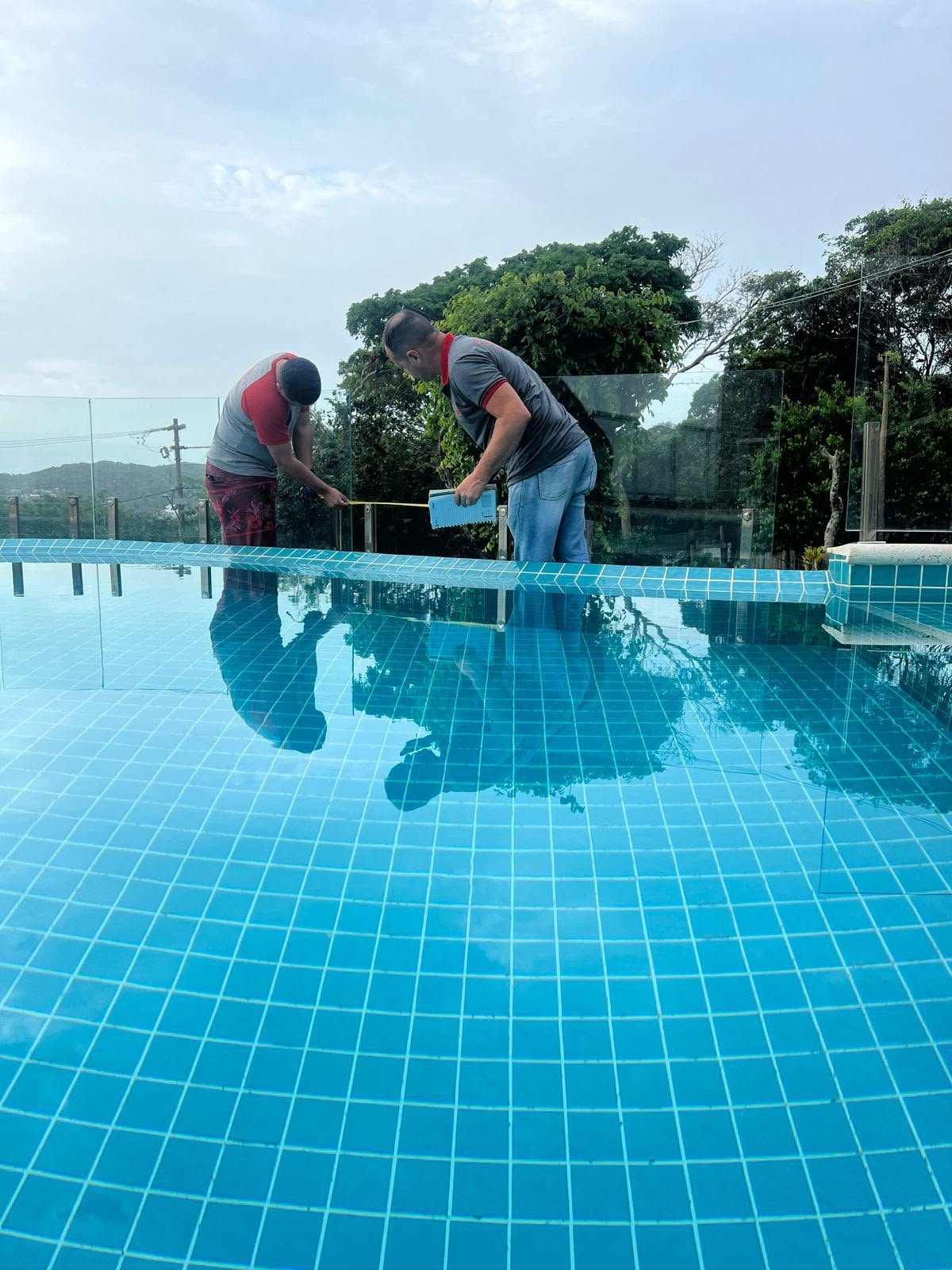 Equipe Dom Angelo instalando guarda-corpo de vidro na borda da piscina